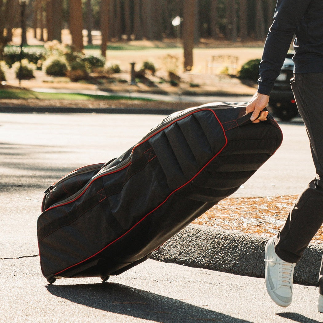 Golfer pulling a BagBoy T720 golf travel cover on its in-line wheels