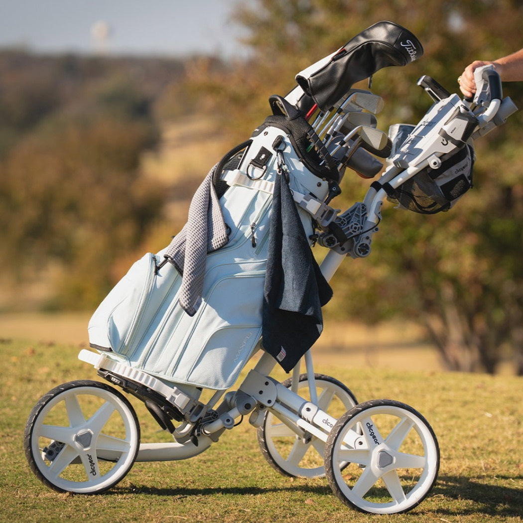 Clicgear 4.5 Golf Push Trolley in White with a golf bag on the course (bag not included)